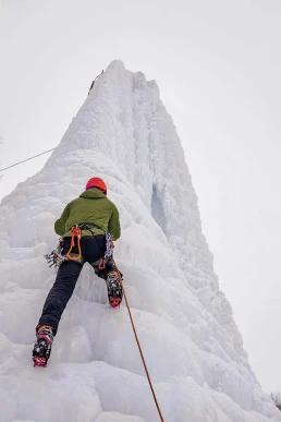 Warum steigen wir auf Berge? Alpinist man with ice tools axe climbing a lar