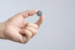 Hand holding round lithium button cell battery