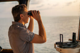 Navigational officer lookout on navigation watch looking through binoculars. Marine industry. COLREG collision regulations