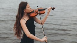 a girl plays the violin in nature